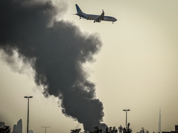 An aircraft prepares for landing as a smoke plume rises from an ongoing fire near Dubai International Airport in Dubai on March 16, 2026.
Photo by AFP

