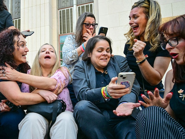 Laura Marquez-Garrett (in gray blazer), plaintiffs' attorney for SMVLC (Social Media Victims Law Center) reacts with victims’ families after jury finds Meta, YouTube liable for social media addiction in LA court on March 25, 2026. Photo by: Frederic J Brown / AFP