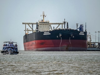 A passenger boat sails past Indian-flagged oil tanker Kashimasan, docked near an offloading terminal at Butcher Island, off the coast in Mumbai on April 1, 2026. (Photo by Punit Paranjpe / AFP