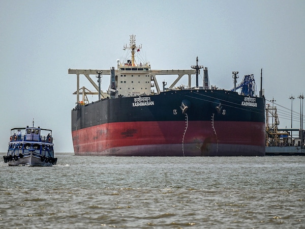 A passenger boat sails past Indian-flagged oil tanker Kashimasan, docked near an offloading terminal at Butcher Island, off the coast in Mumbai on April 1, 2026. (Photo by Punit Paranjpe / AFP