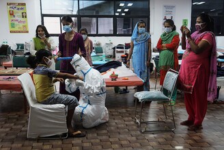 A healthcare worker wearing a PPE suit ties rakhi on the wrist of a Covid-19 child patient at the COVID-19 isolation centre during the Raksha Bandhan festival. Commonwealth Games (CWG) Village and sports complex is temporarily converted into a COVID-19 isolation centre to curb the spread of Coronavirus. A team of healthcare workers readily celebrated Raksha Bandhan festival with the Covid-19 patients inside the Isolation ward.