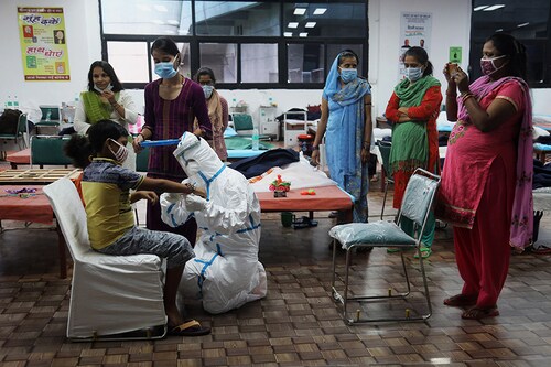 A healthcare worker wearing a PPE suit ties rakhi on the wrist of a Covid-19 child patient at the COVID-19 isolation centre during the Raksha Bandhan festival. Commonwealth Games (CWG) Village and sports complex is temporarily converted into a COVID-19 isolation centre to curb the spread of Coronavirus. A team of healthcare workers readily celebrated Raksha Bandhan festival with the Covid-19 patients inside the Isolation ward.