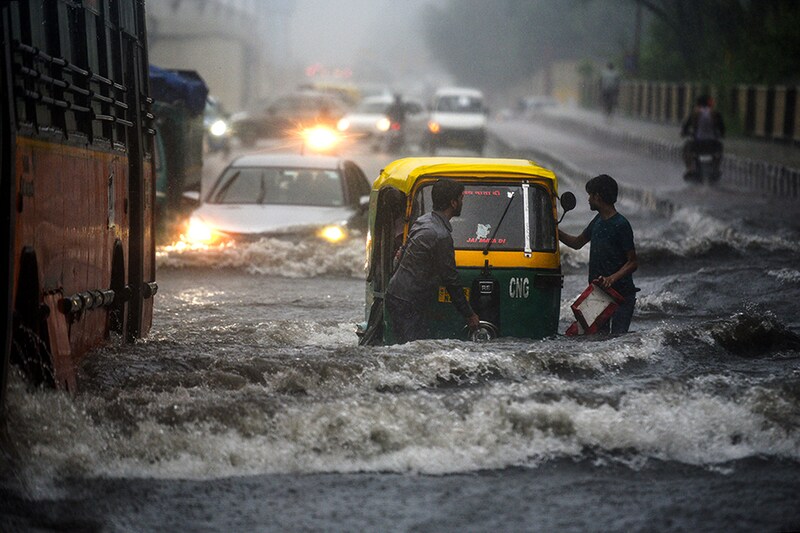 Commuters make their way past a waterlogged stretch after heavy rain along NH 24 near Mayur Vihar II on August 17, 2020 in New Delhi, India