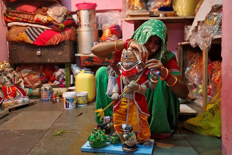 A woman puts a face mask on an idol of Hindu god Ganesh, the deity of prosperity, at her workshop ahead of the Ganesh Chaturthi festival, amidst the coronavirus disease (COVID-19) outbreak, in Ahmedabad, India, August 18, 2020.
