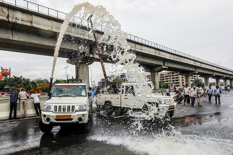 Municipal workers use a water pump to purge a flooded underpass after heavy rains in Gurugram, India