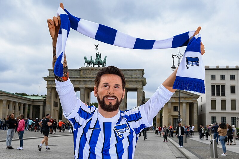 The Madame Tussauds has humorously placed the wax figure of football star Lionel Messi in a jersey from the Berlin club Hertha BSC in front of the Brandenburg Gate. The footballer wants to leave his club FC Barcelona. Where he will play in the future, is not yet known. Messi"s figure has been on display at the waxworks in Berlin since 2018.