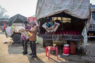 Farmers are seen reading newspapers, near a police road block as they take part during the demonstration. Thousands of farmers from various states march towards the Indian capital to protest against new agricultural laws they say will severely hurt their incomes, according to farmers" union.