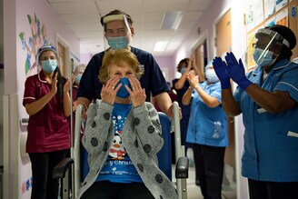 Margaret Keenan, 90, is applauded by staff as she returns to her ward after becoming the first person in Britain to receive the Pfizer/BioNTech COVID-19 vaccine at University Hospital, at the start of the largest ever immunisation programme in the British history, in Coventry, Britain December 8, 2020. Britain is the first country in the world to start vaccinating people with the Pfizer/BioNTech jab.