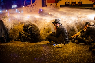 27 December 2020, Israel, Bnei Brak: Israeli policemen use water cannons to disperse a demonstration staged by ultra-Orthodox Jews moments before Israel enters its third nationwide lockdown amid the coronavirus pandemic.