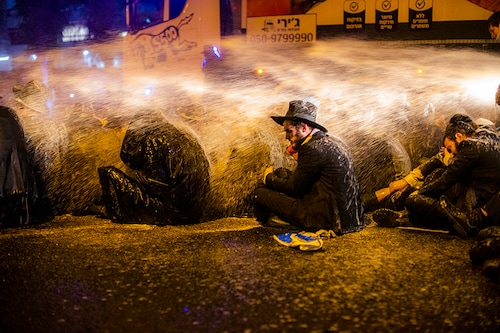27 December 2020, Israel, Bnei Brak: Israeli policemen use water cannons to disperse a demonstration staged by ultra-Orthodox Jews moments before Israel enters its third nationwide lockdown amid the coronavirus pandemic.