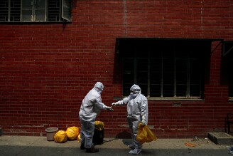 Medical workers help each other as they get ready to remove their Personal Protective Equipment (PPE), at a school which was turned into a centre to conduct tests for the coronavirus disease (COVID-19), amidst the spread of the disease, in New Delhi, India, June 30, 2020.