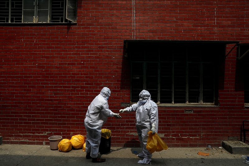 Medical workers help each other as they get ready to remove their Personal Protective Equipment (PPE), at a school which was turned into a centre to conduct tests for the coronavirus disease (COVID-19), amidst the spread of the disease, in New Delhi, India, June 30, 2020.