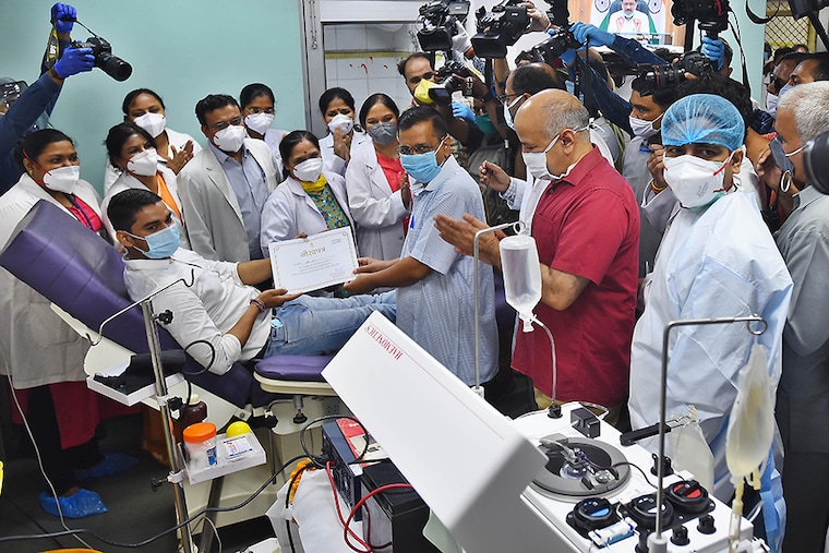 Delhi Chief Minister Arvind Kejriwal is accompanied by Deputy Chief Minister Manish Sisodia as he hands a certificate to a person making a plasma donation during the inauguration of the Delhi government"s second plasma bank at the Lok Nayak Jai Prakash (LNJP) Hospital, on July 14, 2020 in New Delhi, India.