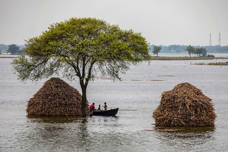 A woman with two children rows a small boat in a flooded field in Bhagalpur district in the eastern state of Bihar, India, July 28, 2020.