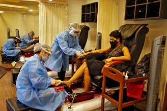 Beauticians wearing protective gear tend to their customers inside a parlor at a shopping mall after authorities allowed the reopening of malls, during an extended nationwide lockdown to slow the spreading of the coronavirus disease (COVID-19), in Ahmedabad, India, June 8, 2020â£â£
