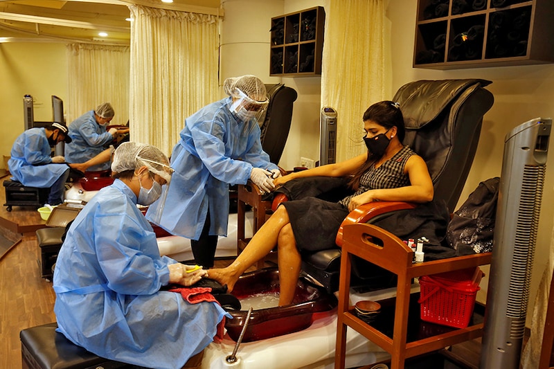 Beauticians wearing protective gear tend to their customers inside a parlor at a shopping mall after authorities allowed the reopening of malls, during an extended nationwide lockdown to slow the spreading of the coronavirus disease (COVID-19), in Ahmedabad, India, June 8, 2020â£â£