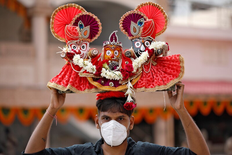 A devotee, wearing a protective face mask, carries idols of the Hindu God Jagannath, his sister Subadhra and brother Balabhadra, as he arrives to attend the annual Rath Yatra, or chariot procession, amidst the coronavirus disease (COVID-19) outbreak, in Ahmedabad, India, June 23, 2020.