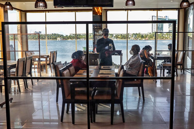 A waiter wearing a protective face mask serves customers at the Cafe Ekante restaurant, after authorities eased lockdown restrictions that were imposed to slow the spread of the coronavirus disease (COVID-19), on the outskirts of Kolkata, India, June 25, 2020.