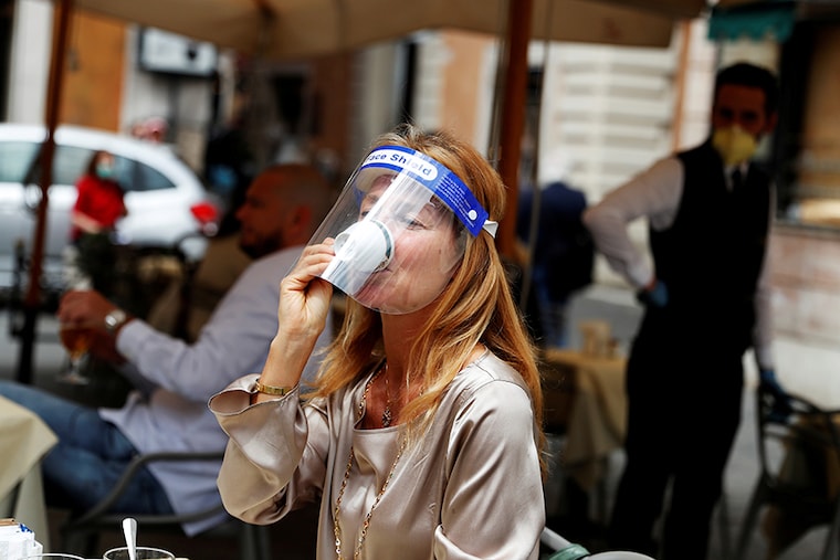 A woman wearing a face shield drinks coffee at a cafe as Italy eases some of the lockdown measures put in place during the coronavirus disease (COVID-19) outbreak, in Rome, Italy.
