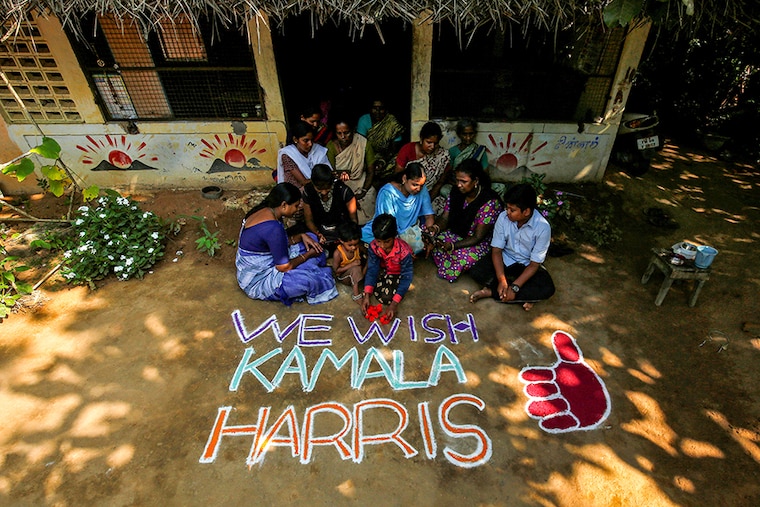 Women and children sit next to a message for U.S. Democratic vice presidential nominee Kamala Harris in Painganadu near the village of Thulasendrapuram, where Harris" maternal grandfather was born and grew up, in Tamil Nadu state, India, November 5, 2020.