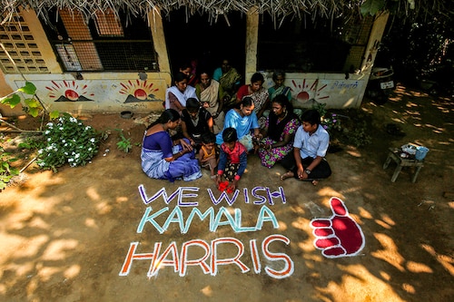 Women and children sit next to a message for U.S. Democratic vice presidential nominee Kamala Harris in Painganadu near the village of Thulasendrapuram, where Harris" maternal grandfather was born and grew up, in Tamil Nadu state, India, November 5, 2020.