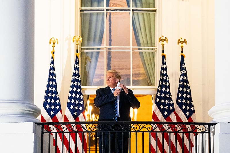 President Donald Trump removes his mask as he stands on the Truman Balcony upon returning to the White House Monday, Oct. 5, 2020, after testing positive for COVID-19 and spending four days at the the Walter Reed Medical Center in Bethesda, Md.