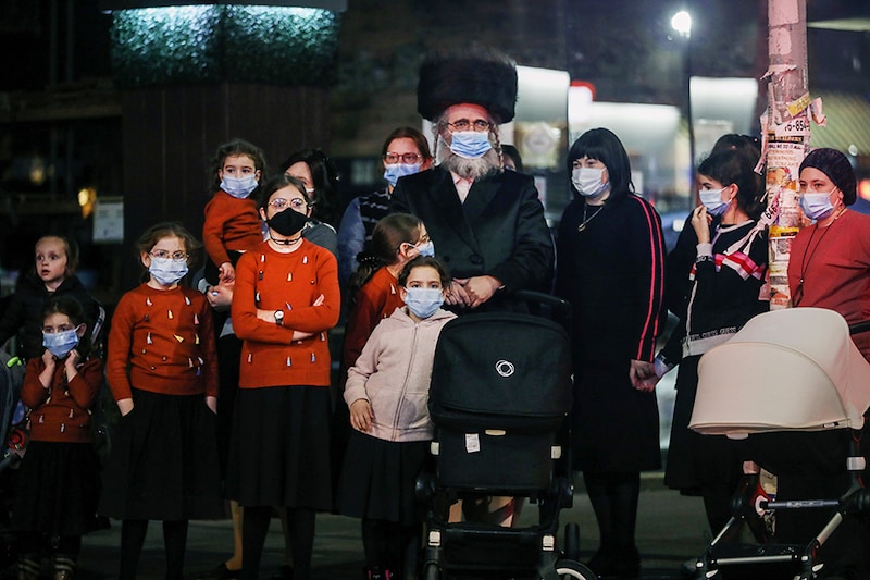 A family watches as groups of protesters gather in the Brooklyn neighborhood of Borough Park to denounce lockdowns of their neighborhood due to a spike in COVID-19 cases on October 07, 2020 in New York City. Borough Park is one of numerous Brooklyn neighborhoods that are witnessing a rising number of COVID-19 cases as New York City continues to trend down to around a one percent overall infection rate. Many of the neighborhoods experiencing a spike in cases are Orthodox Jewish neighborhoods which have had issues with authorities in limiting large funerals and weddings. New York City Mayor Bill de Blasio has announced plans to close nonessential businesses and schools in nine neighborhoods where positive COVID-19 rates have been higher than 3 percent.
