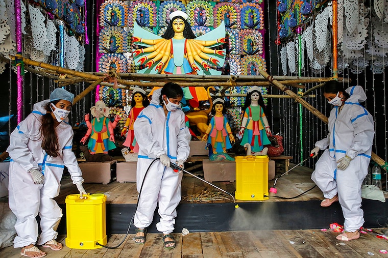 Women wearing personal protective equipment (PPE) sanitize a "pandal" or a temporary platform, ahead of Durga Puja festival, amidst the spread of the coronavirus disease (COVID-19), in Kolkata, India, October 16, 2020.