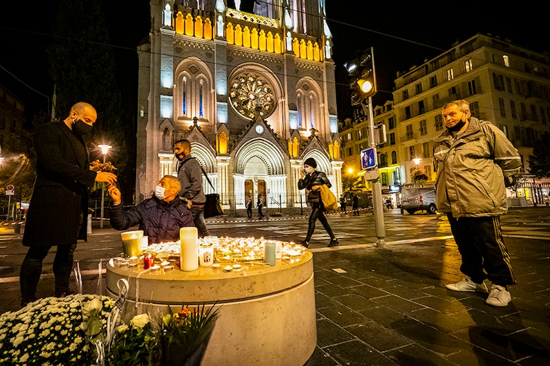 People pay tributes at night in front of Notre Dame Basilica on October 29, 2020 in Nice, France. A man armed with a knife fatally attacked three people in the Notre-Dame church in Nice, located in the heart of the city.