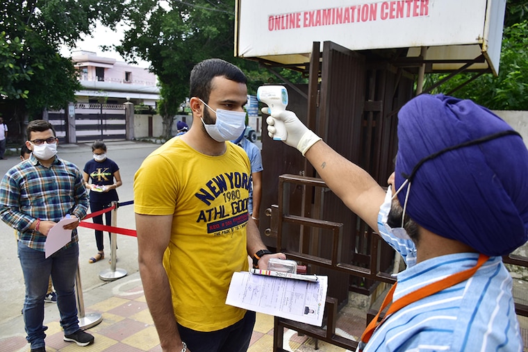 An exam official checks the body temperature of a candidate appearing for JEE Mains, at an exam centre, on Albert Road on September 1, 2020 in Amritsar, India. The Joint Entrance Examination-Main (JEE) for admission to IITS begins today across the country amid a surge in coronavirus cases and opposition by several non-BJP ruled states. Mandatory face masks and gloves, staggered entry and seating to ensure social distancing are some of the guidelines students have been asked to follow. The JEE is scheduled to be held between September 1 and September 6. The National Eligibility Cum Entrance Test (NEET) entrance exam for medical courses, will be held on September 13.
