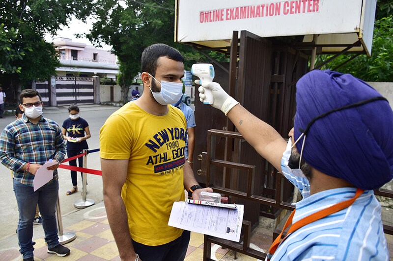 An exam official checks the body temperature of a candidate appearing for JEE Mains, at an exam centre, on Albert Road on September 1, 2020 in Amritsar, India. The Joint Entrance Examination-Main (JEE) for admission to IITS begins today across the country amid a surge in coronavirus cases and opposition by several non-BJP ruled states. Mandatory face masks and gloves, staggered entry and seating to ensure social distancing are some of the guidelines students have been asked to follow. The JEE is scheduled to be held between September 1 and September 6. The National Eligibility Cum Entrance Test (NEET) entrance exam for medical courses, will be held on September 13.