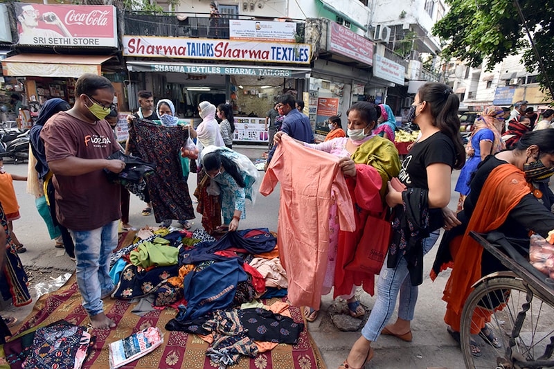 People look to buy clothes from a roadside stall, at Mangal Bazar at Bhogal on September 15, 2020 in New Delhi, India. Streets are crowded despite directions from Delhi Disaster Management Authority (DDMA) to ensure social distancing norms.