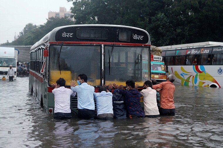 People push a bus through a waterlogged road after heavy rainfall in Mumbai, India, September 23, 2020.