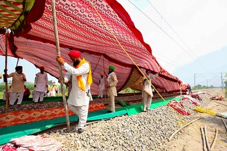 Farmers erect a temporary shade on railway tracks to take shelter from the sun as they block the rail tracks during a protest against farm bills passed by India"s parliament, in Devi Dasspura village on the outskirts of Amritsar, India, September 24, 2020.