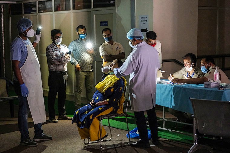 A health worker takes a swab sample under mobile phone torchlight during a power cut at a temporary Covid-19 testing site at the Jawahar Lal Nehru Stadium in New Delhi, India, on Friday, April 16, 2021. India is in the grip of a second wave of Covid-19 infections that has caught the federal and state governments unprepared, with local media reporting that patients are dying due to a shortage of oxygen and hospital beds.