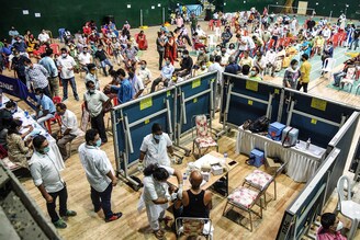 A medical worker (bottom C) inoculates a man with a dose of the Covaxin Covid-19 coronavirus vaccine at an indoor stadium in Guwahati on April 22, 2021.