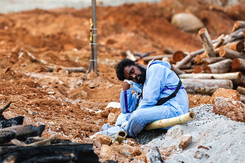 A man wearing PPE (Personal Protection Equipment) waits to perform the last rites of a deceased relative in a new crematorium built to cremate the dead due to Covid-19 on April 28, 2021 in Bengaluru, India. on April 28, 2021 in Bengaluru, India. Residents of Indian cities have been leaving in droves to return to villages and towns across the country, sparking fresh fears that Covid-19 infections will spread to areas where health infrastructure is either poor or non-existent. India"s deadly wave of infections is out of control, and the health ministry reported 379,257 new cases and 3645 deaths in the last 24 hours.