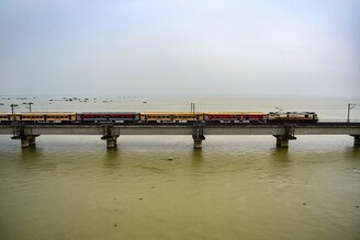 A passenger train crosses a bridge over the flooded river Ganga as water levels in the Ganga and Yamuna rivers rise in Allahabad on August 11, 2021. River is flowing above the danger mark since few days now.