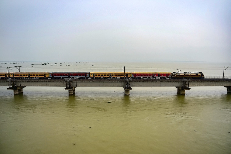 A passenger train crosses a bridge over the flooded river Ganga as water levels in the Ganga and Yamuna rivers rise in Allahabad on August 11, 2021. River is flowing above the danger mark since few days now.