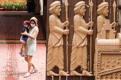 A Parsi woman and her child step out of a fire temple adorned with carvings of priests on Persian New Year, also known as "Jamshedji Navroz" in Mumbai, India, August 16, 2021. Zoroastrians migrated to India, settling in Gujarat & other states in India, upon fleeing from Islamic persecution of Persia.