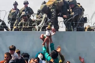 A baby is handed over to the American army over the perimeter wall of the airport for it to be evacuated, in Kabul, Afghanistan, August 19, 2021, in this still image taken from a video obtained from social media. Video taken August 19, 2021.