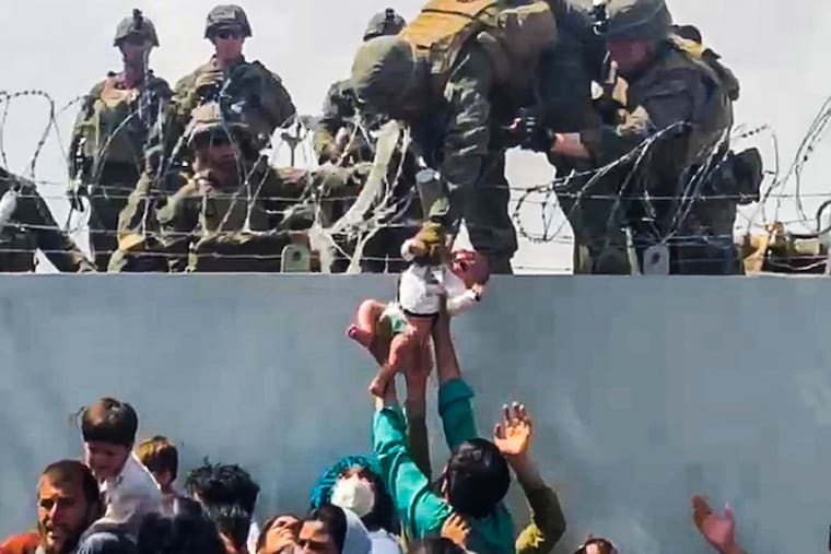 A baby is handed over to the American army over the perimeter wall of the airport for it to be evacuated, in Kabul, Afghanistan, August 19, 2021, in this still image taken from a video obtained from social media. Video taken August 19, 2021.