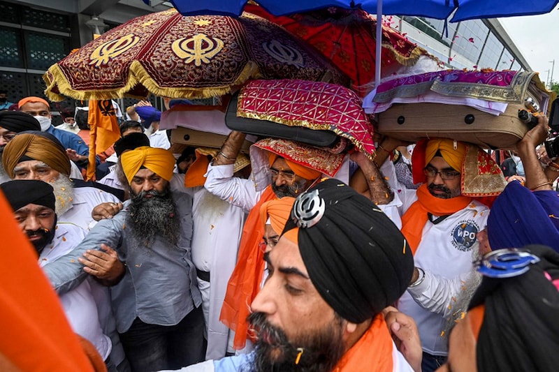 Men carry the Guru Granth Sahib, the holy book of the Sikhs after it was brought back by the Afghan Sikh evacuees from Afghanistan, upon their arrival at the Indira Gandhi International Airport in New Delhi on August 24, 2021 following the Taliban’s military takeover of Afghanistan.