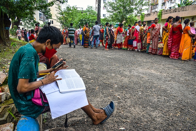 A boy is snapped doing his online classes while waiting for his vaccination, outside the West Bengal state health vaccination camp in Kolkata.