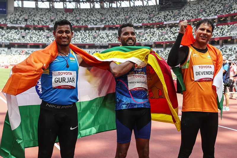 Bronze Medallist Sundar Singh Gurjar of India, Gold Medallist Dinesh Priyan Herath Mudiyanselage of Sri Lanka and Silver Medallist Devendra Jhajharia of India celebrate with the flags of their countries after competing in the men"s javelin throw (F46) event at the Tokyo Paralympics on August 30, 2021.