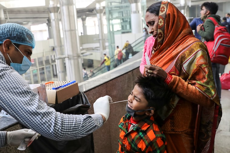 A healthcare worker collects a Covid-19 test swab sample from a boy at a bus terminal in New Delhi, India, December 6, 2021. With the arrival of the Omicron variant, The Indian Medical Association has warned the health authorities of a massive third wave, if adequate measures aren"t taken.
