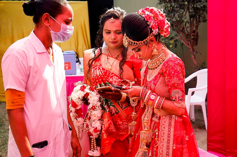 A bride searches her coronavirus disease (COVID-19) vaccination certificate in her mobile phone to show it to a healthcare worker at her wedding venue during a vaccination drive and checking of vaccination certificates, in Ahmedabad, India.