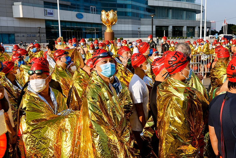 Swimmers cover themselves with thermal blankets before the start of a cross-harbour swimming event at Victoria Harbour, Hong Kong, China December 12, 2021.