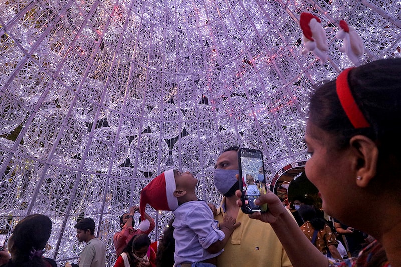 People take pictures inside an illuminated Christmas tree at a mall during Christmas celebrations in Mumbai, India, December 25, 2021.