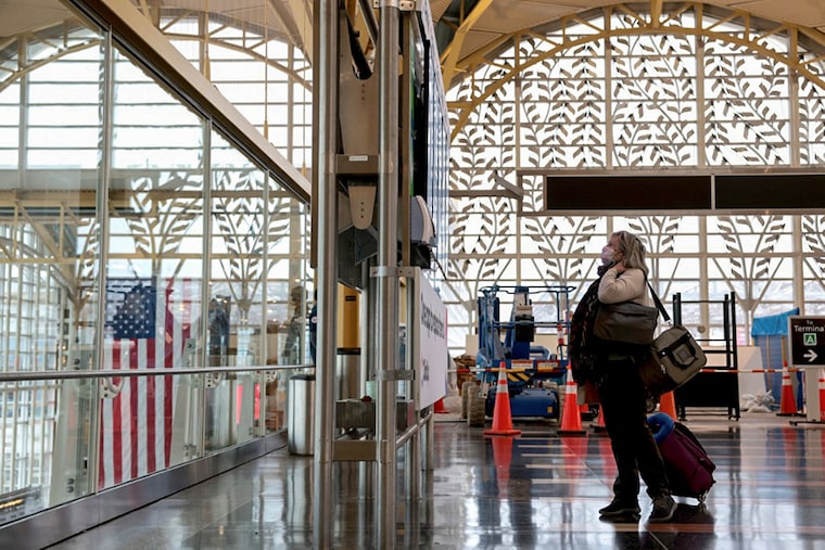 A woman looking at departure and arrival times on a flight information display system shows departure times at the Ronald Reagan Washington National Airport on December 27, 2021 in Arlington, Virginia. According to media reports, at least 2,600 more flights were canceled Monday amid the surge in coronavirus cases, which have affected the staff within airlines.